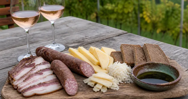 Gedeckter Holztisch mit Brettljause und Weingläsern